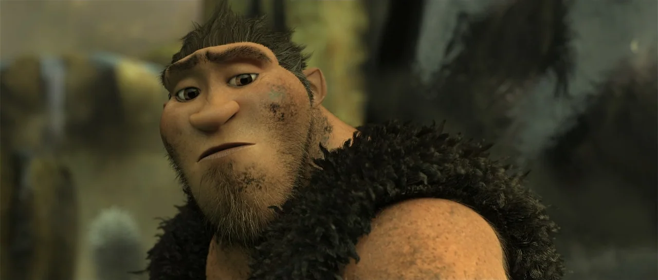 The Croods (2013) movie still: closeup — A prehistoric environment features earthy textures and soft natural light. A muscular man in a fur pelt…