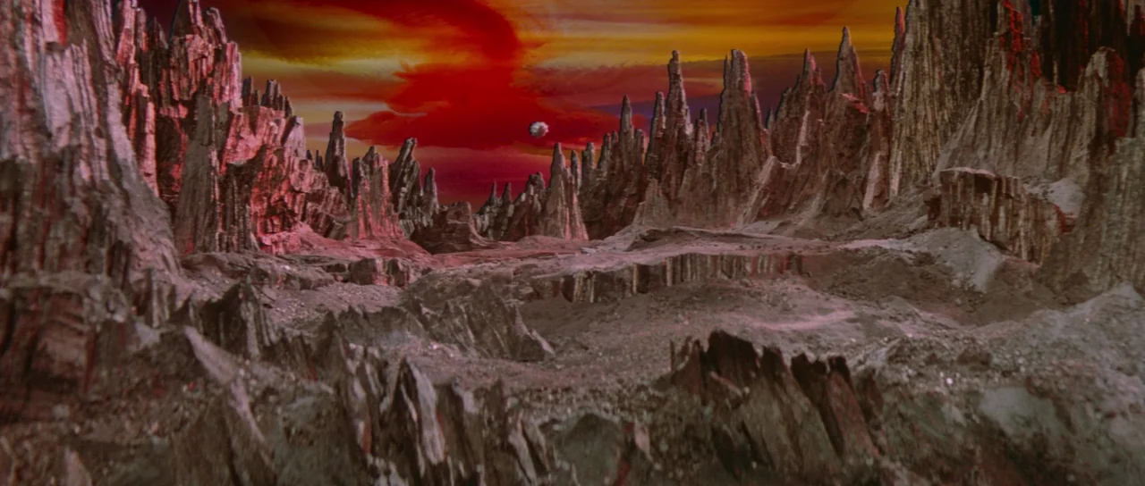 Flash Gordon (1980) movie still: establishing — A desolate alien planet features jagged, upright rock formations and a barren cratered surface. A…