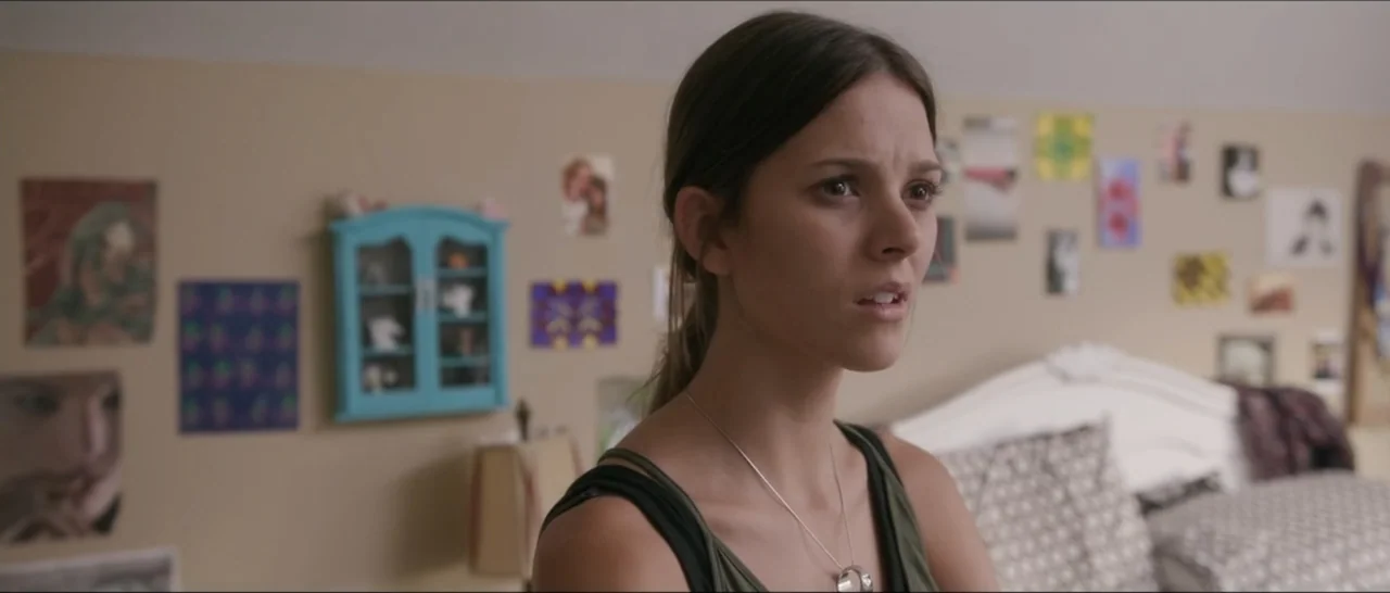 If You're Gone (2019) movie still: medium — A bedroom wall is covered in various small printed photographs and paper artwork. A young woman turns…