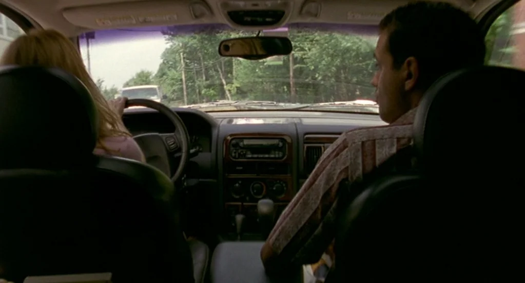 The Station Agent (2003) movie still: medium — The interior of a mid-2000s SUV seen from the backseat. A man and woman occupy the front seats while…