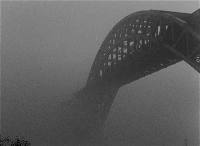 Summer with Monika (1953) movie still: wide — A massive steel arch bridge rises above a thick layer of heavy fog. The structure of the bridge is…