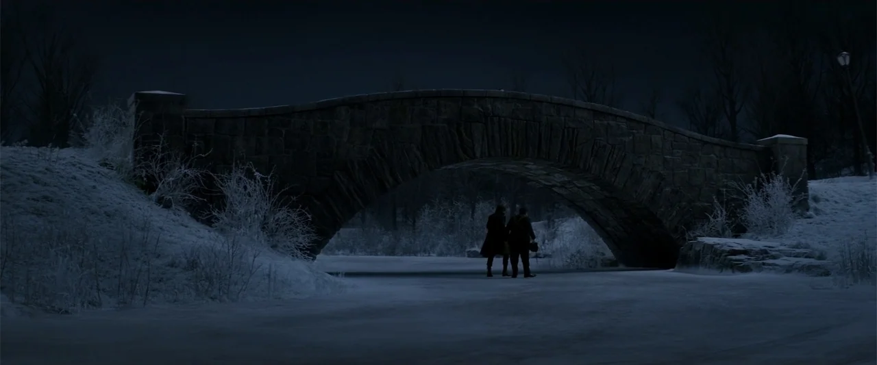 Fantastic Beasts and Where to Find Them (2016) movie still: wide — A snow-covered stone bridge spans a frozen stream under a dark winter night sky.…