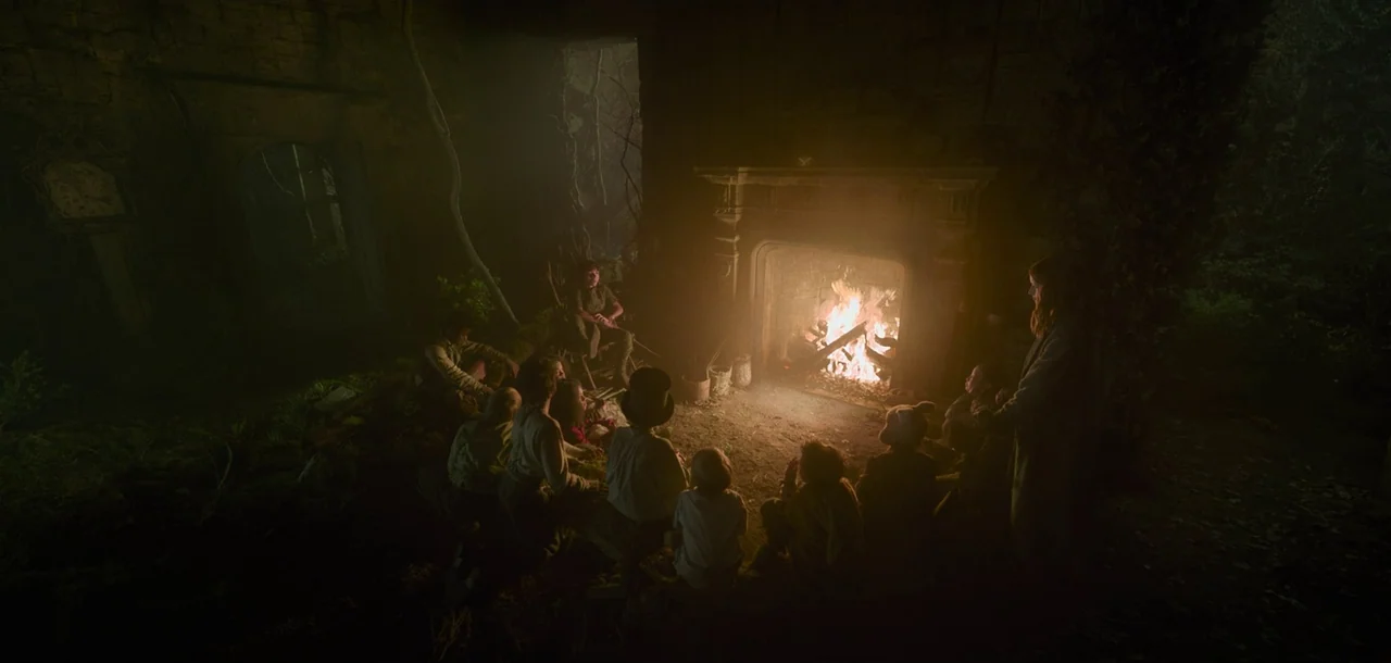 Peter Pan & Wendy (2023) movie still: wide — A dark, dilapidated interior of a stone building features an open fireplace in ruins. A group of…