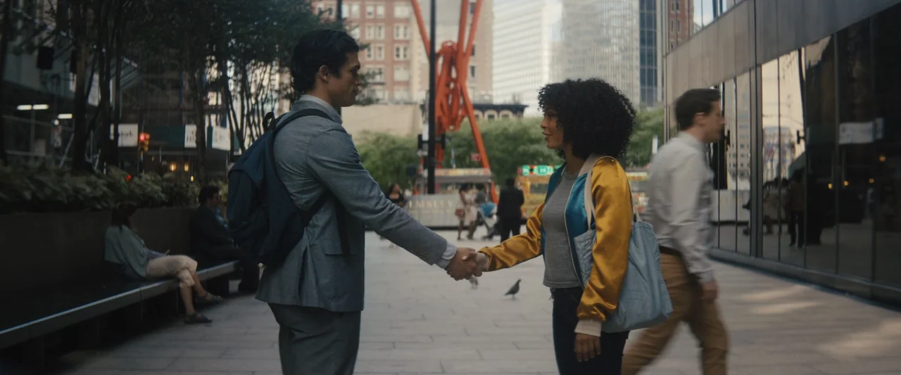 The Sun Is Also a Star (2019) movie still: medium — A metropolitan pedestrian area with glass buildings and an orange sculpture in the background. A…