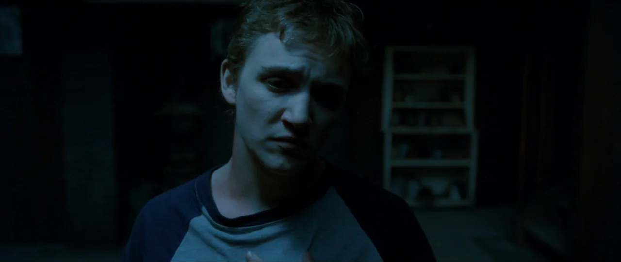 The Haunting in Connecticut (2009) movie still: medium — A dimly lit, unfinished basement contains a white wooden storage unit in the shadows. A…