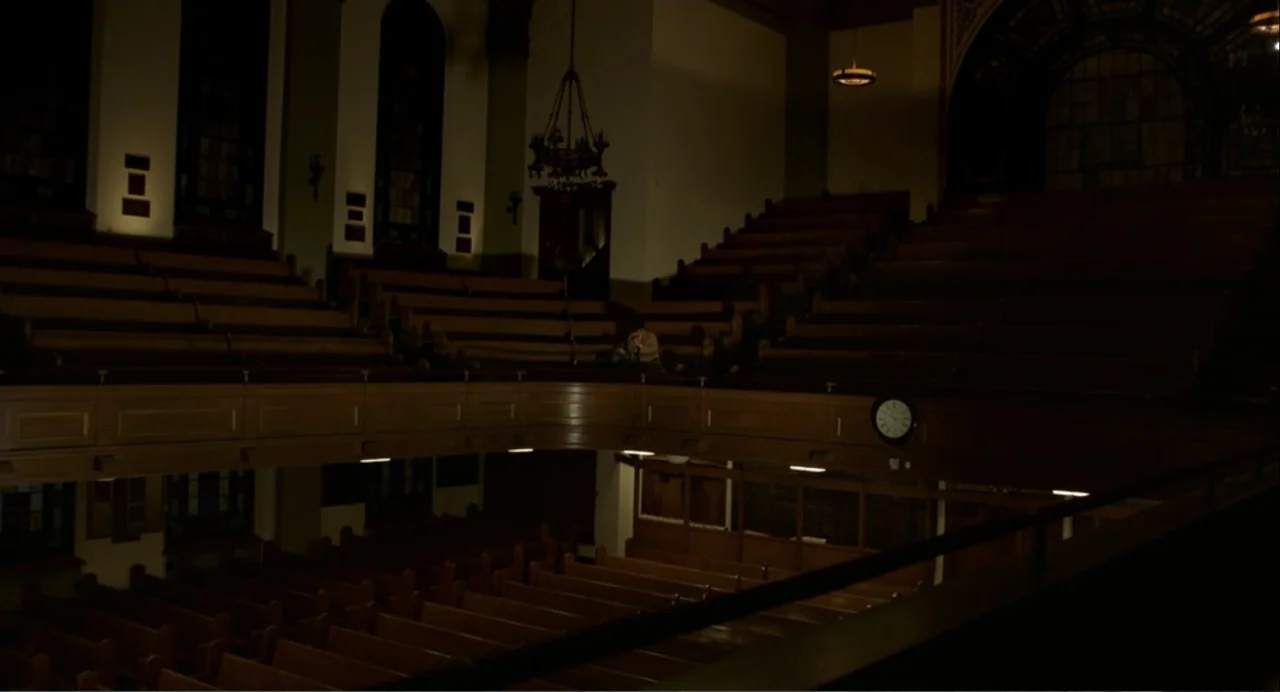 Norman: The Moderate Rise and Tragic Fall of a New York Fixer (2016) movie still: wide — A dark, expansive wooden auditorium features tiered seating…