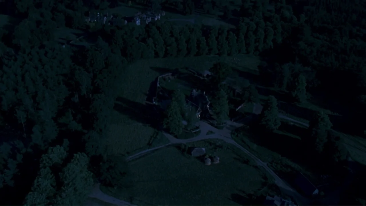 Nanny McPhee and the Big Bang (2010) movie still: establishing — An aerial view looks down on a dark rural estate at night. Trees surround a central…