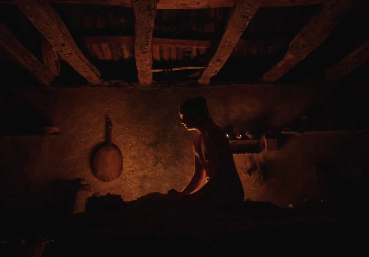 You Won’t Be Alone (2022) movie still: medium — A rustic earthen-walled room features heavy wooden ceiling beams and a hanging wooden scoop. A…
