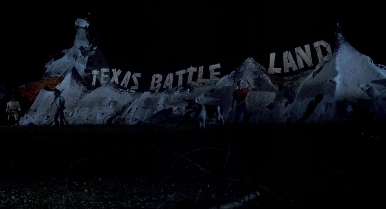 The Texas Chainsaw Massacre 2 (1986) movie still: wide — A night scene shows an outdoor amusement attraction with large carved wooden letters…