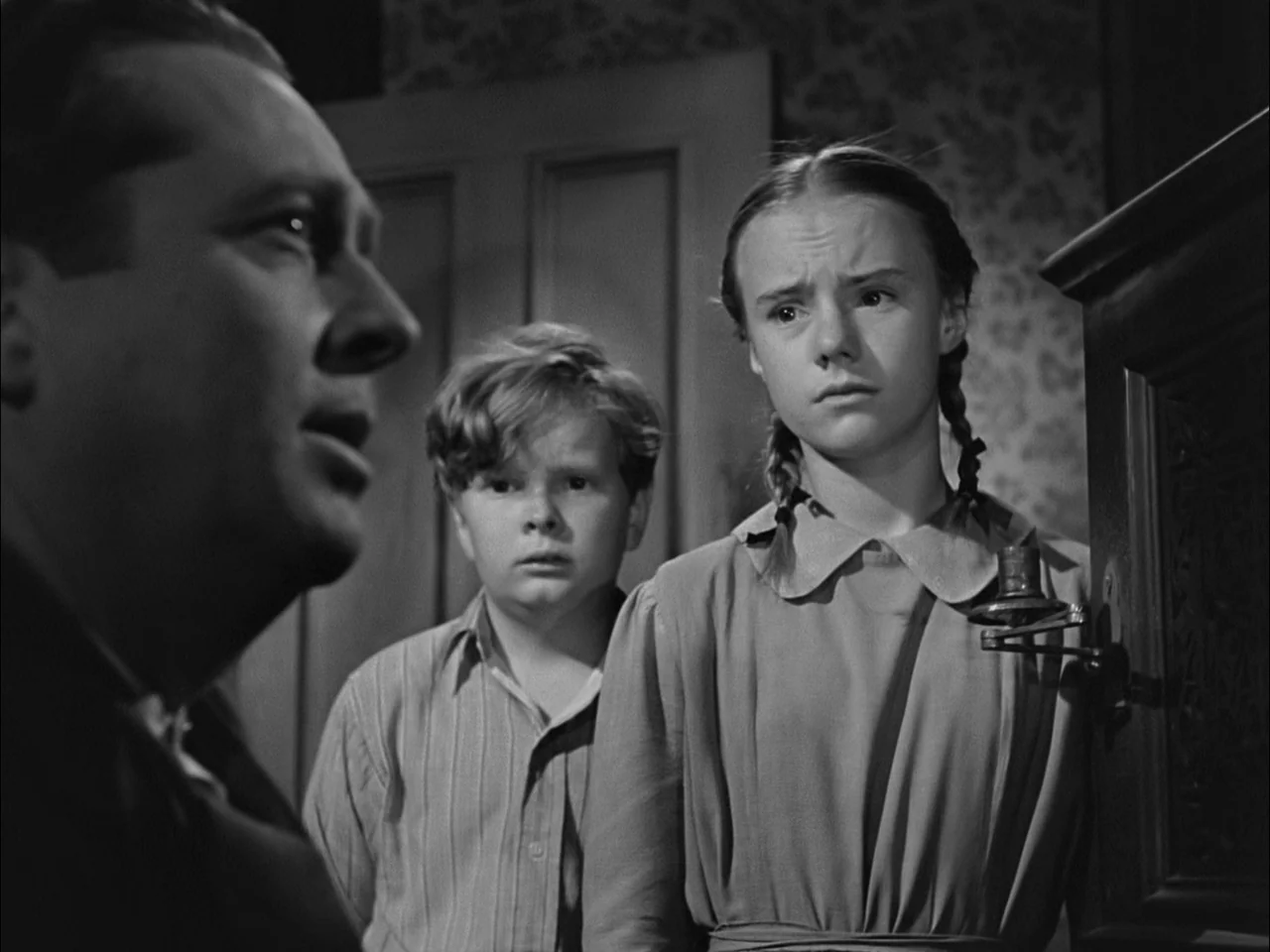 A Tree Grows In Brooklyn (1945) movie still: medium — A domestic space features a patterned wallpaper background and a dark wood cabinet element. An…