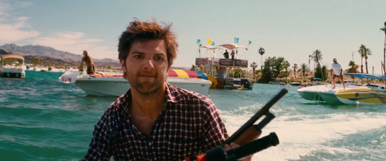 Piranha 3D (2010) movie still: medium — A sunny lake environment with recreational motorboats and a floating platform in the distance. A man in a…