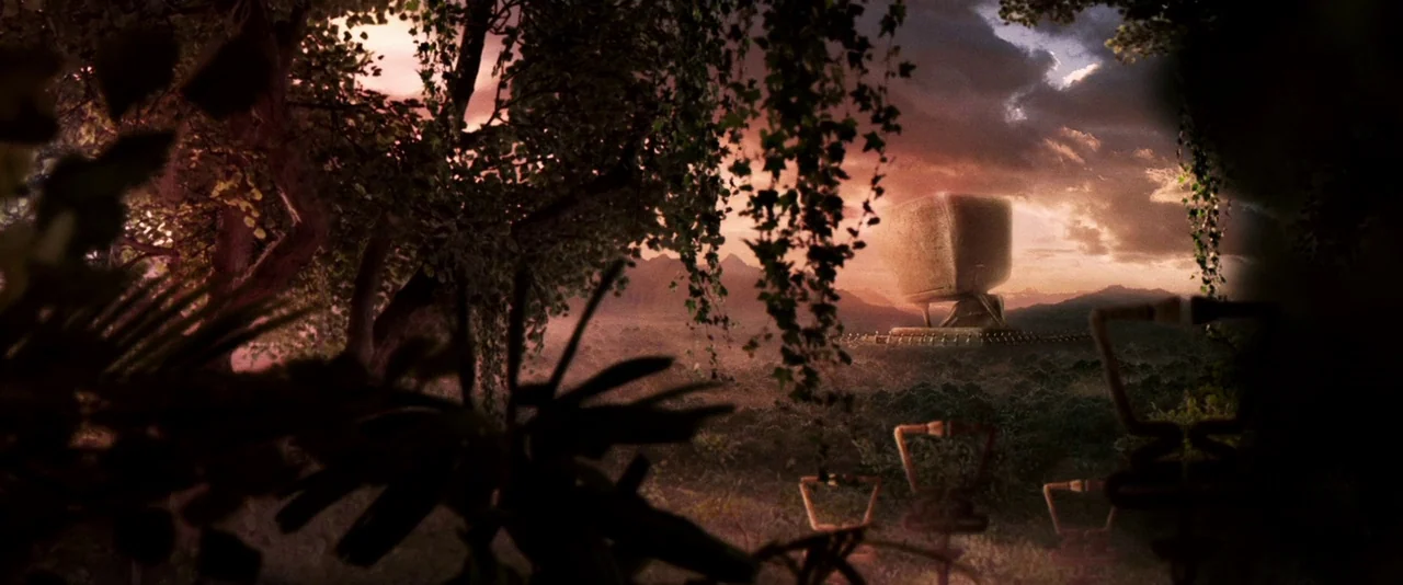 A Hitchhiker’s Guide To The Galaxy (2005) movie still: establishing — A dark, silhouetted foreground of leafy trees frames a vast plain at dusk. A…