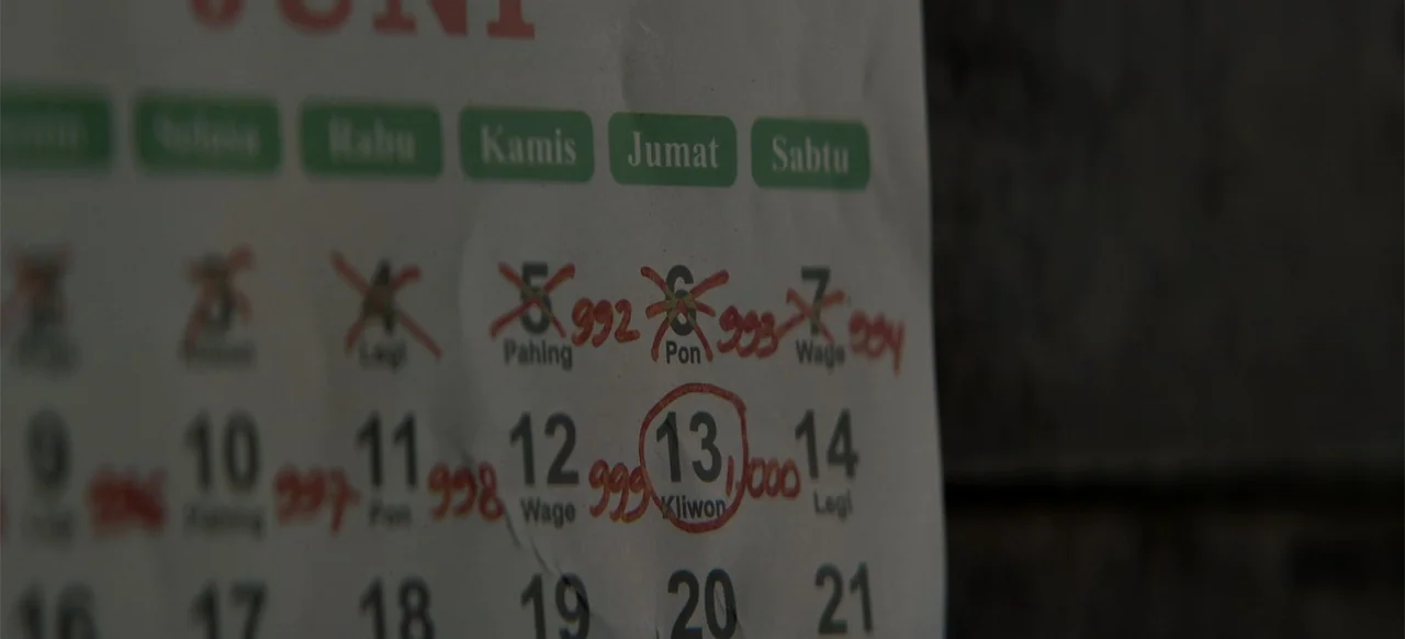 A Thousand Days (2023) movie still: closeup — A close-up of a paper wall calendar with handwritten red markings. Certain dates are crossed out and…