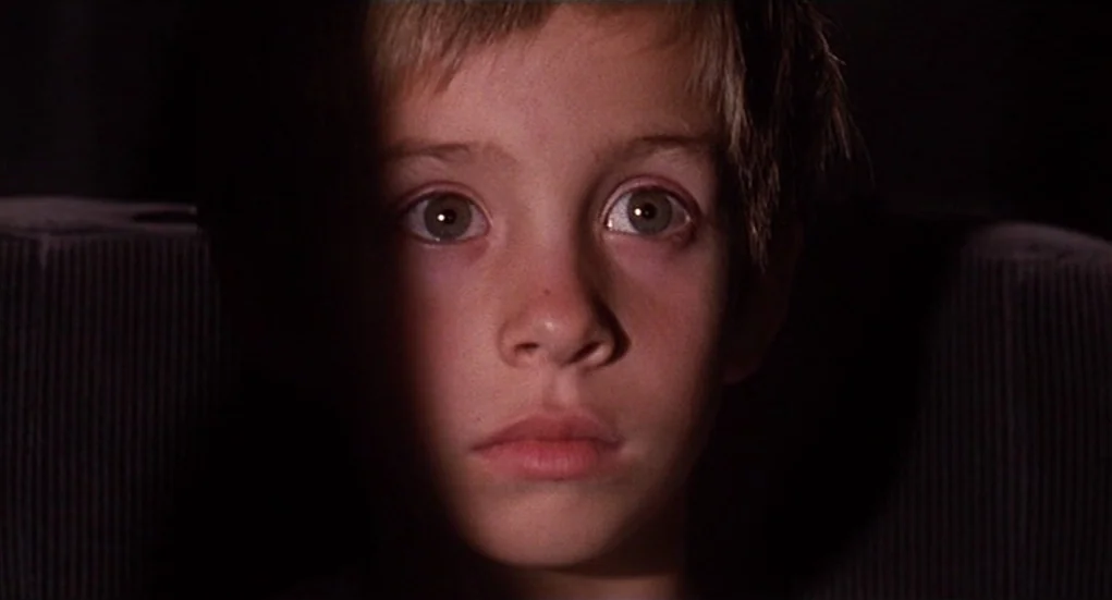 The Heart Is Deceitful Above All Things (2004) movie still: closeup — A dark, enclosed space with a child seated in front of a projection source.…