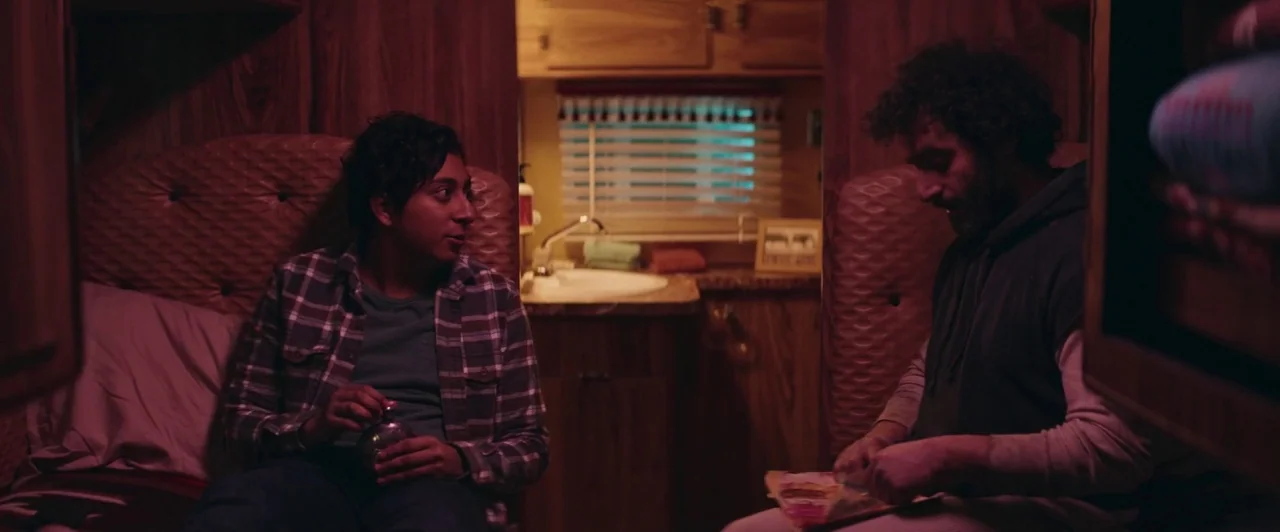 The Long Dumb Road (2018) movie still: medium — A cramped camper van interior features wood-paneled walls and a small sink area.
