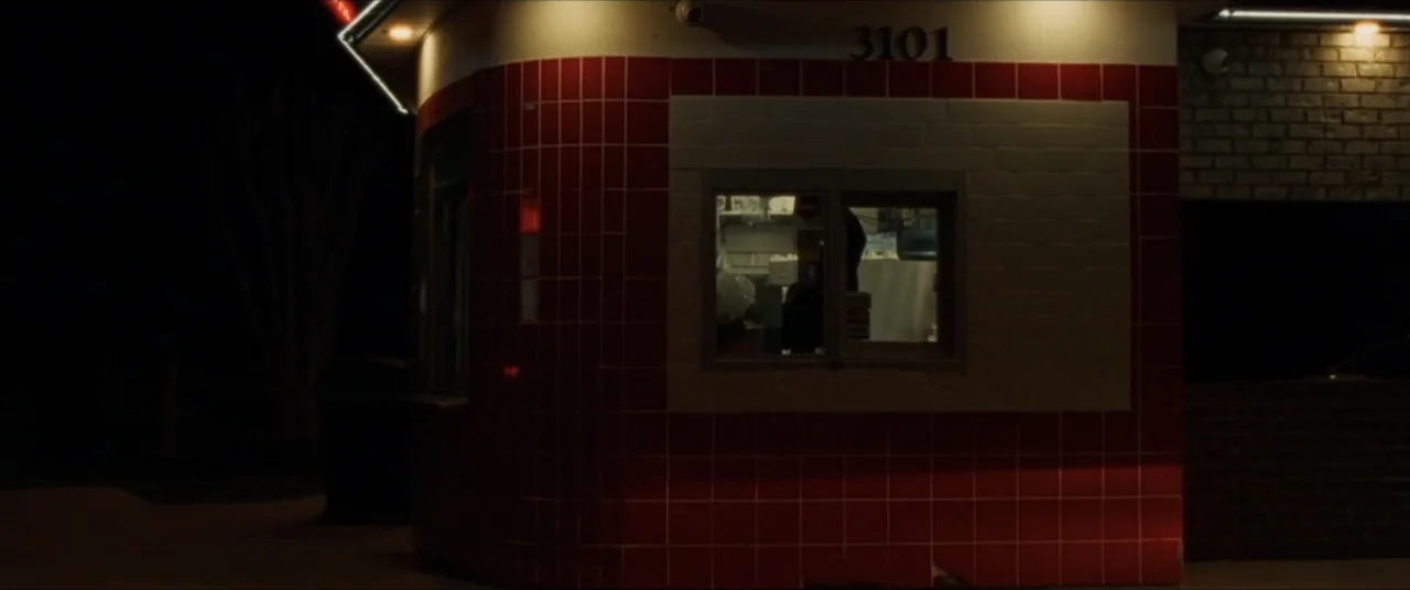 Sermon on the Mount (2019) movie still: wide — A dark exterior corner of a brick and red-tiled building features a small window. The number 3101 is…