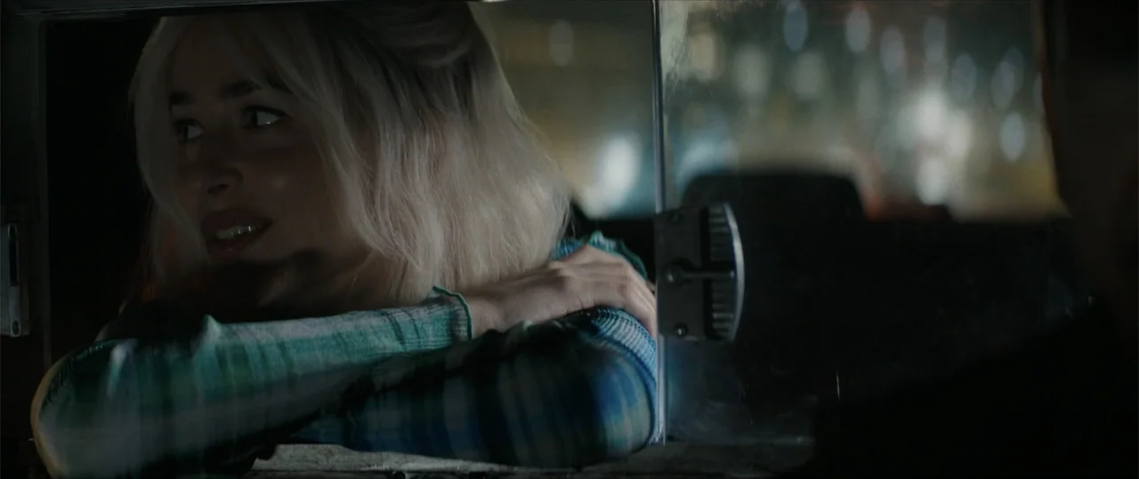 Daddio (2024) movie still: medium — A woman leans on the car door ledge inside a vehicle at night. She rests her chin on her arms while looking…