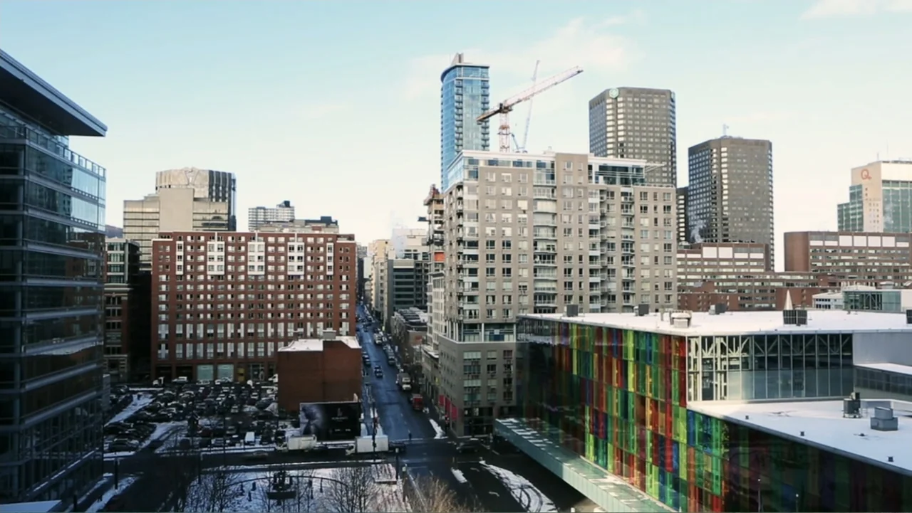 Code of Trust (2019) movie still: establishing — An urban cityscape features high-rise residential buildings and a street grid covered in snow.…