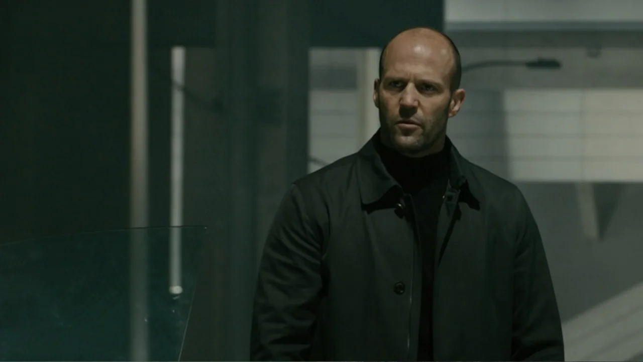 Furious 7 (2015) movie still: medium — A modern parking structure features concrete pillars and minimalist industrial architecture. A man in a dark…