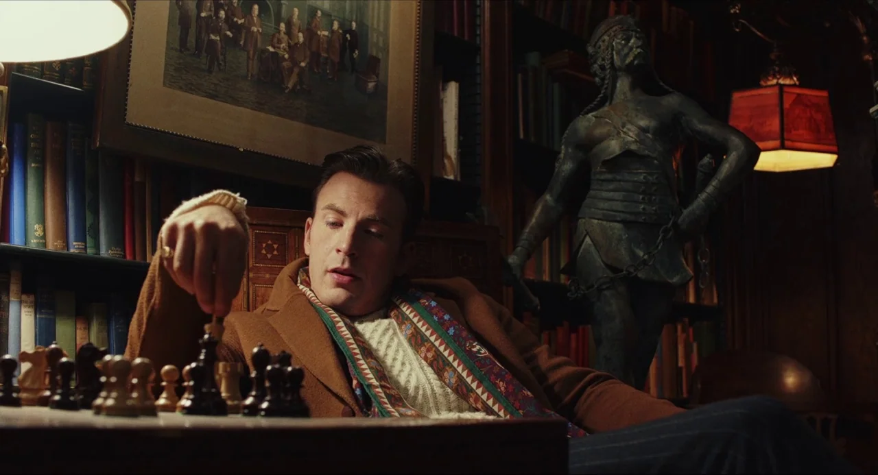 Knives Out (2019) movie still: medium — A dark wood-paneled library features floor-to-ceiling bookshelves, framed artwork, and an ornate bronze…