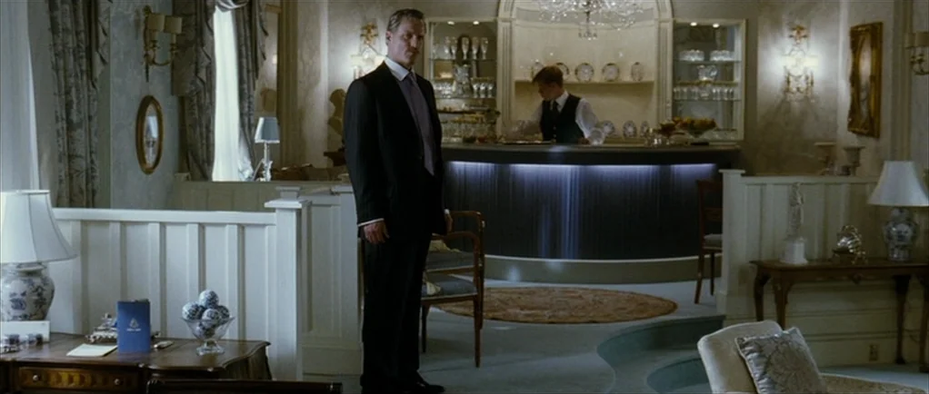 The Walker (2007) movie still: fullbody — An opulent hotel interior features decorative molding, soft carpeting, and a prominent semicircular bar. A…