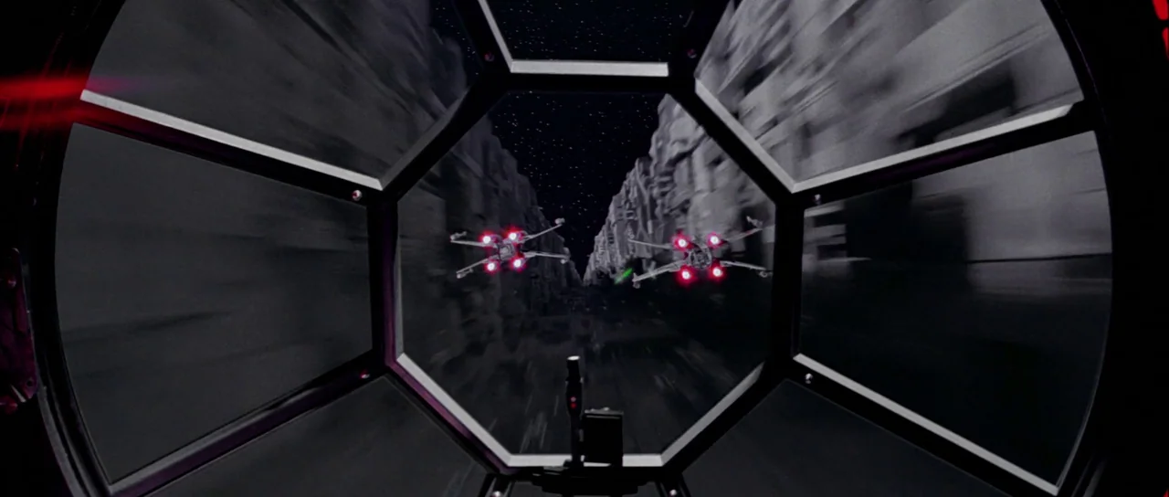 Star Wars (1977) movie still: wide — A view from inside a cockpit looking out at a deep space structural trench. Two starfighters fly through the…