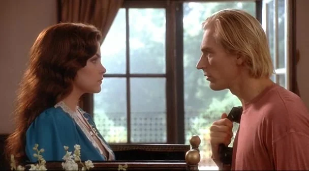 Boxing Helena (1993) movie still: medium — A man and woman face each other in a room with large window panes. Sunlight illuminates their profiles as…
