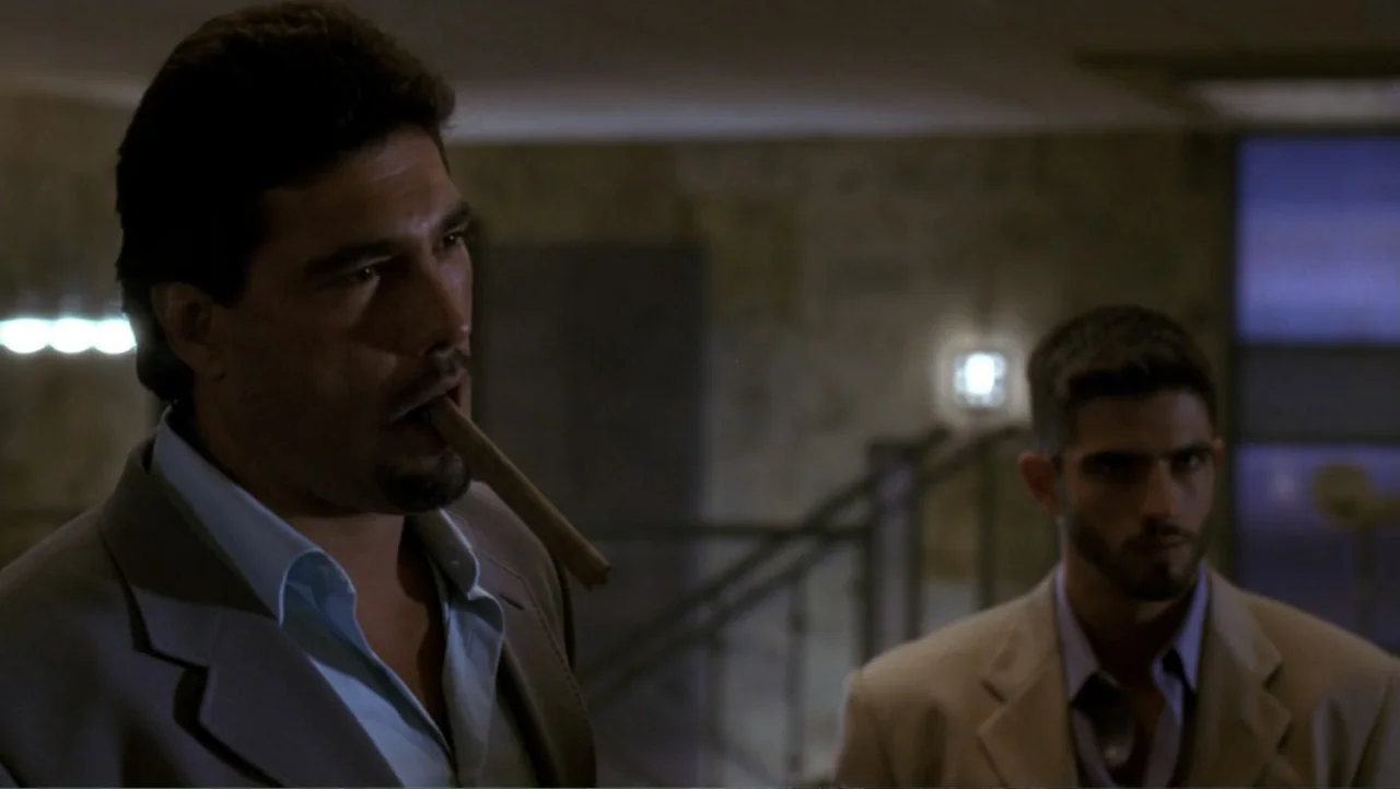 The Punisher (2004) movie still: medium — An interior lobby space with stone walls and a blurred staircase in the distance. Two men stand together,…