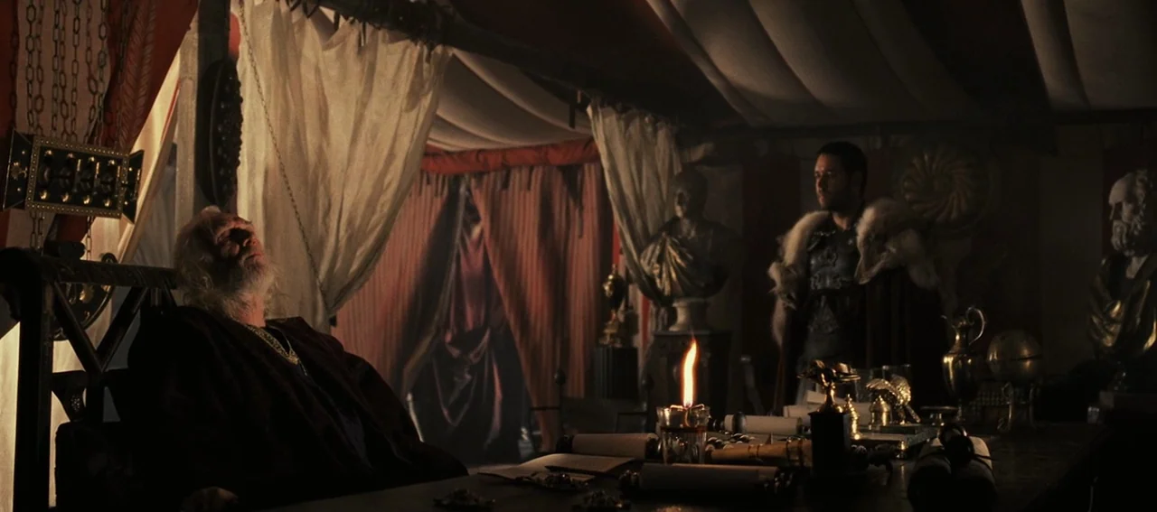 Gladiator (2000) movie still: wide — A Roman military tent is furnished with draped fabrics, stone busts, and wooden furniture. An elderly man rests…