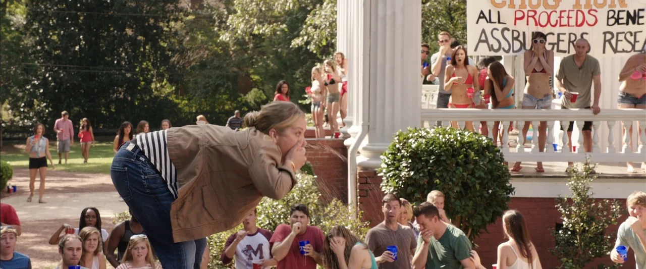 Vacation (2015) movie still: medium — A college house front lawn features a crowd of students watching a party event. A woman stands in the…