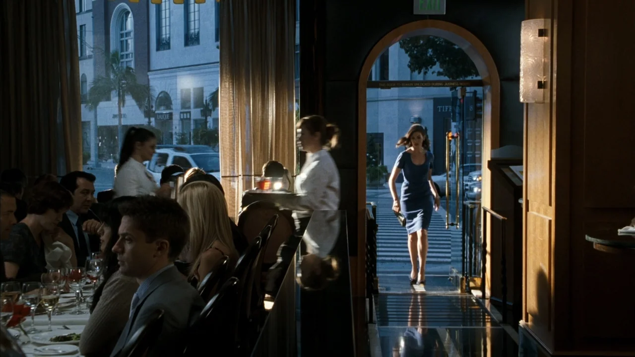 F Valentine's Day (2026) movie still: medium — A high-end restaurant with dark wood trim and patrons dining at white-clothed tables. A woman in a…