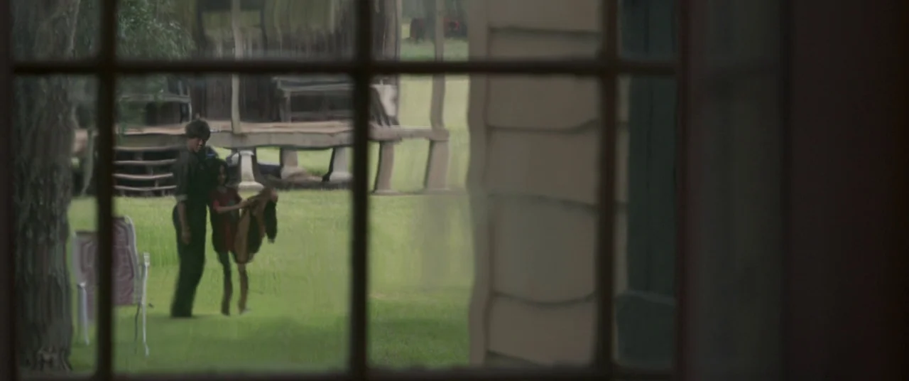 Captain Marvel (2019) movie still: wide — A green lawn is visible through a multi-pane glass window frame. An adult woman and a child stand together…