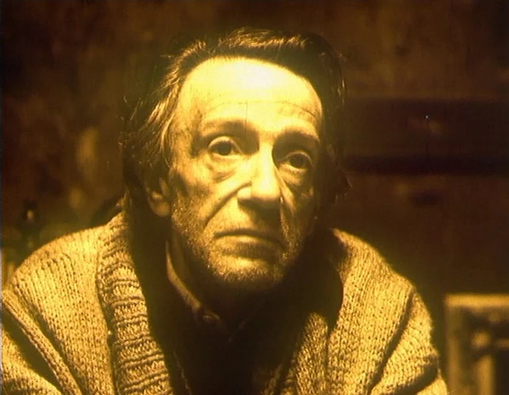 Dead Man’s Letters (1986) movie still: closeup — An elderly man is framed in a dark, warm-toned interior space. He looks toward the camera while…