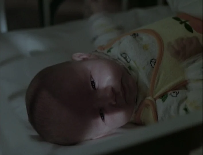 Camera Buff (1979) movie still: closeup — An infant rests on white bedding inside a dark space. The subject stares upwards.