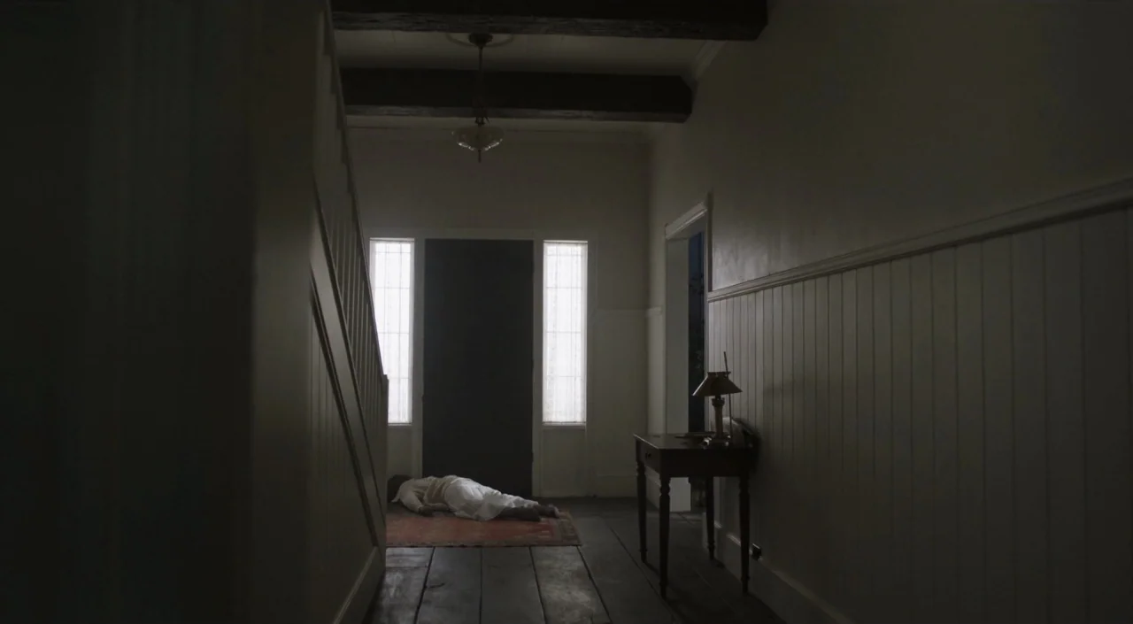 I Am The Pretty Thing That Lives In The House (2016) movie still: wide — A dimly lit wooden foyer features a staircase on the left and a small…