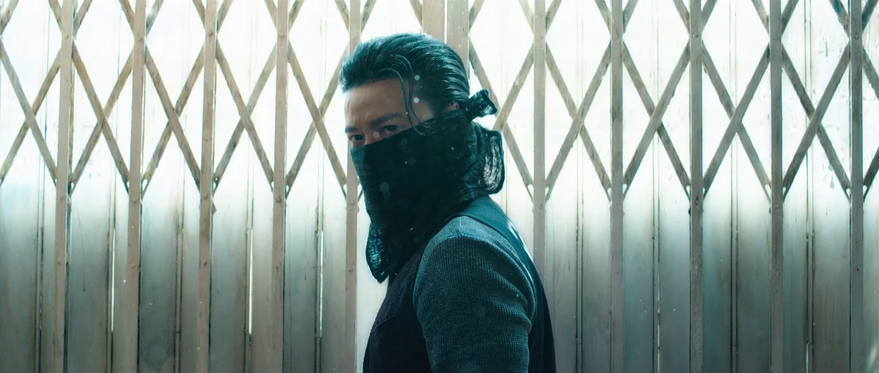 Ip Man 3 (2015) movie still: medium — An interior space features a metal diamond-pattern gate backlit by a bright light source. A man wearing a dark…