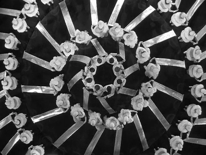 42nd Street (1933) movie still: establishing — A performance stage features a large group of dancers arranged in a spiral pattern. Each dancer holds…