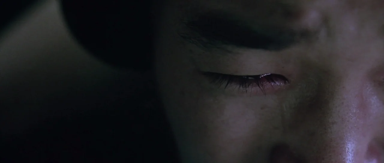 Oldboy (2003) movie still: closeup — A close-up view of a person's eye area in a darkened space. The subject's eye is partially closed with skin…