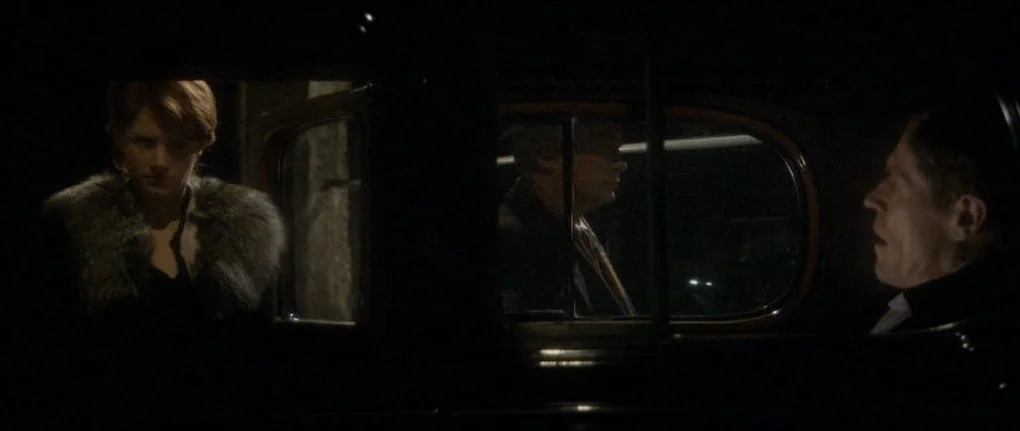 Manderlay (2005) movie still: medium — The interior of a vintage car at night is dimly lit with high contrast. A man and a woman sit facing each…