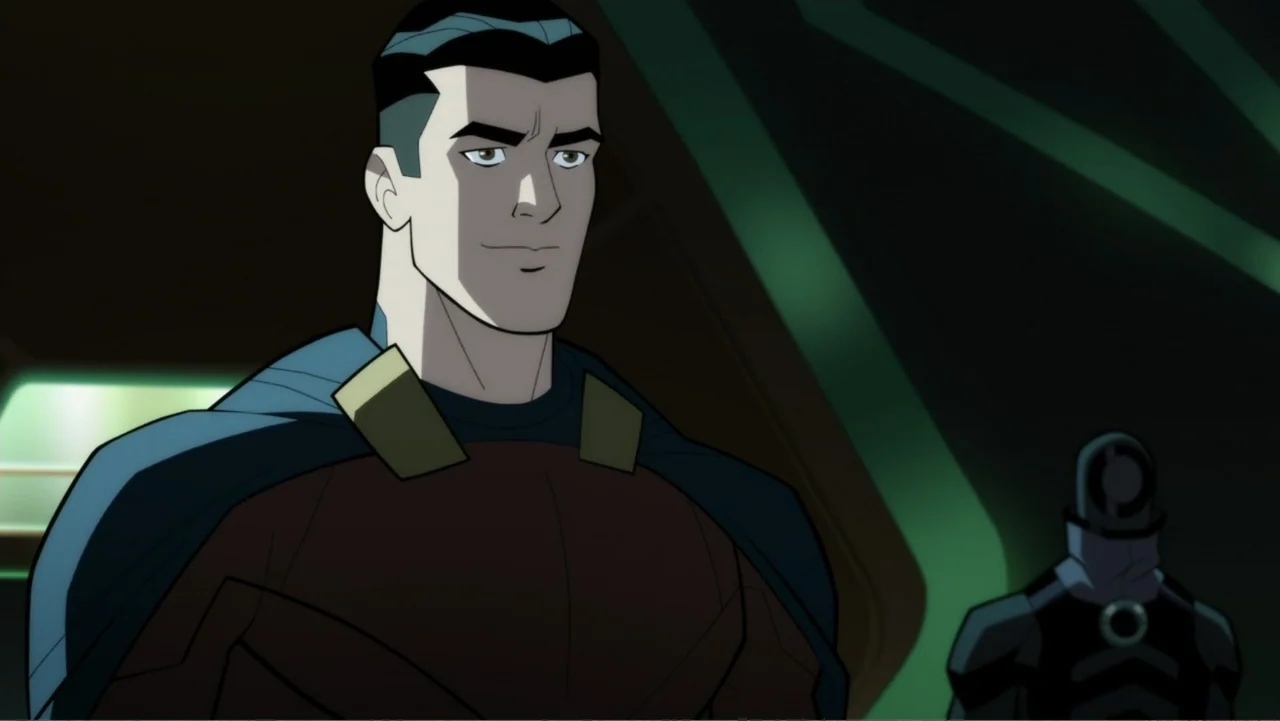 Legion of Super-Heroes (2023) movie still: medium — A dimly lit futuristic corridor features angular green wall panels and dark shadows. A man in a…