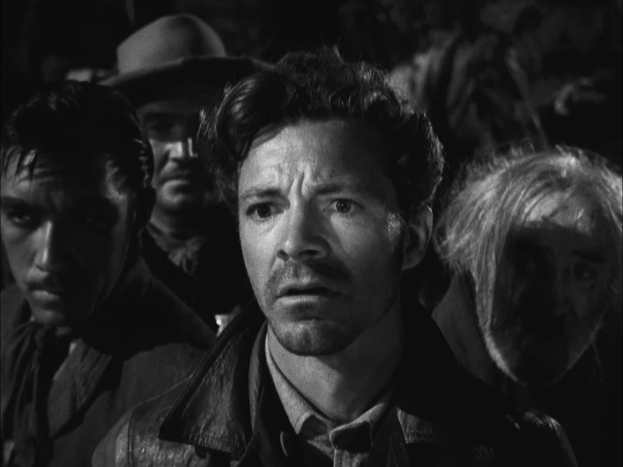 The Ox-Bow Incident (1942) movie still: medium — Four men stand close together in a dark nighttime setting. The central figure looks forward with a…