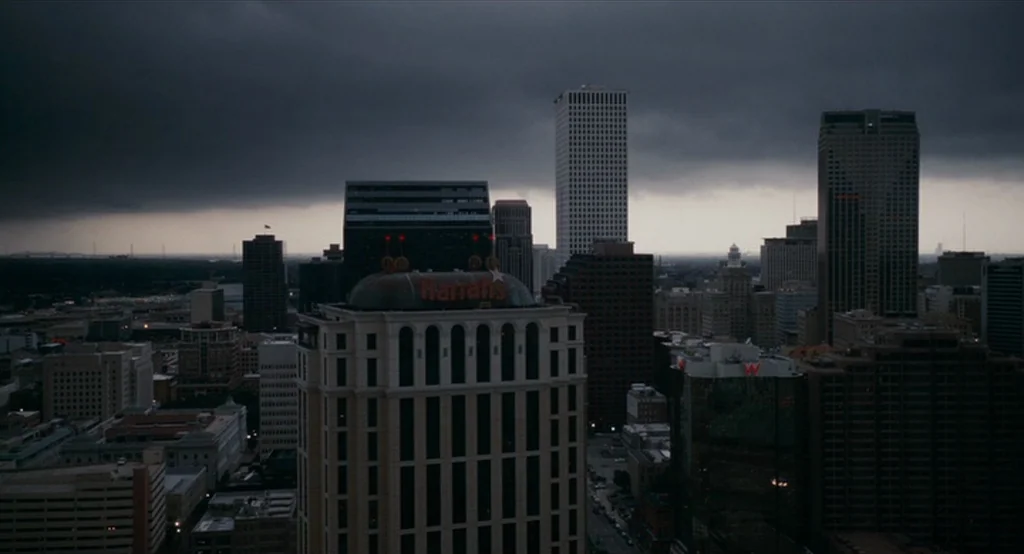 Bad Lieutenant: Port Of Call New Orleans (2009) movie still: establishing — A dense urban skyline is silhouetted against a dark, overcast sky filled…