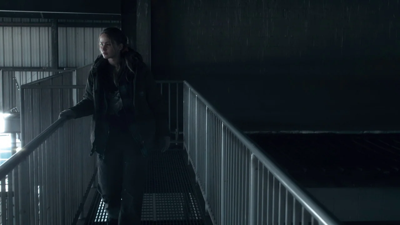 Winter’s Bone (2010) movie still: medium — An elevated industrial walkway with grey metal grating floors and vertical safety railings. A young woman…