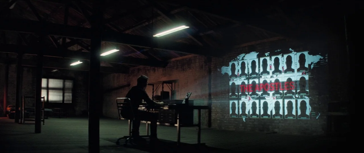 Mission: Impossible – Fallout (2018) movie still: wide — An industrial space with brick walls and exposed ceiling beams holds a lone desk. A man…