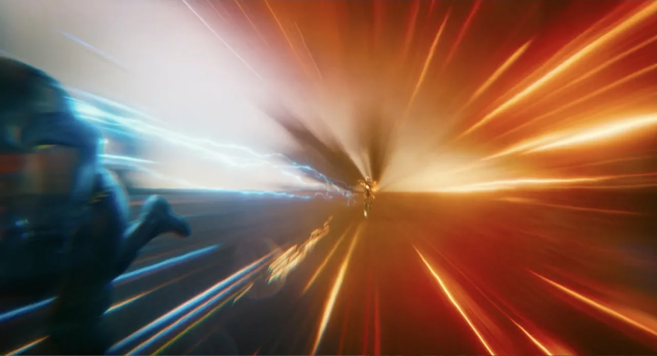 The Flash (2023) movie still: wide — A surreal tunnel filled with glowing light streaks and high-velocity motion blur. Two figures in suits sprint…