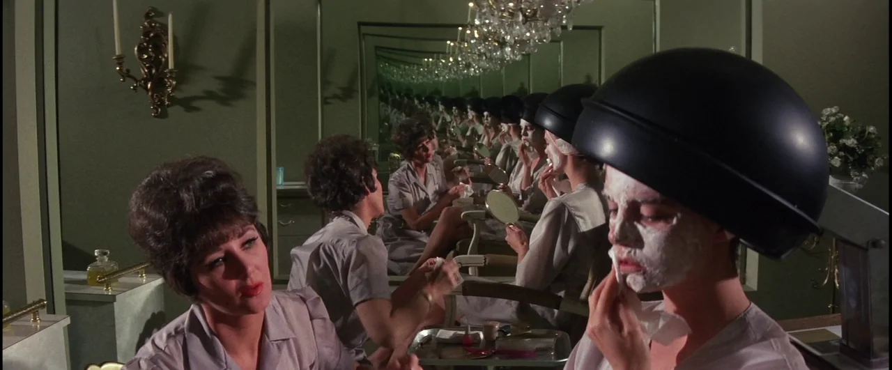 Point Blank (1967) movie still: medium — A 1960s beauty salon features rows of vanity mirrors and glass chandeliers. Multiple women wear smocks and…