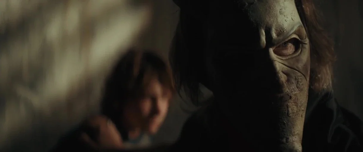 The Black Phone (2021) movie still: closeup — A dimly lit, windowless space with textured walls and deep shadows. The foreground features a close-up…