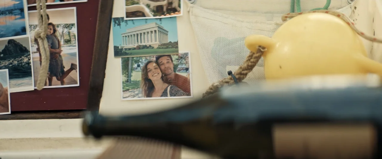 Great White (1998) movie still: closeup — A close-up view of a corkboard displaying several candid photographs inside a small vessel. A yellow…