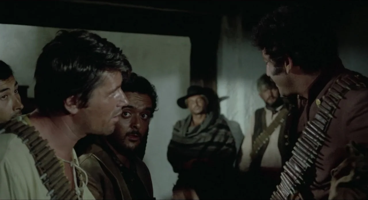 A Stranger in Town (1943) movie still: medium — A dimly lit room with white plaster walls contains a group of armed men. Three men stand in the…