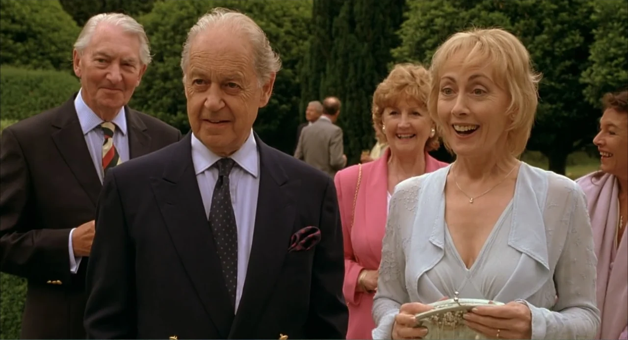 Scoop (2024) movie still: medium — A group of older adults stand outdoors in a lush green park setting. The subjects are dressed for a formal social…